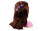 Puppe mit langen, braunen Haaren, geflochtener Frisur und lila kronenförmigen Haarspangen.