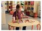 Ein junges Mädchen spielt an einem Tisch mit einem LUPILU® Körper-Puzzle aus Holz.