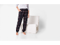 Dunkle karierte Pyjamahose mit grauem T-Shirt und Bündchen, neben einem weißen Sessel.