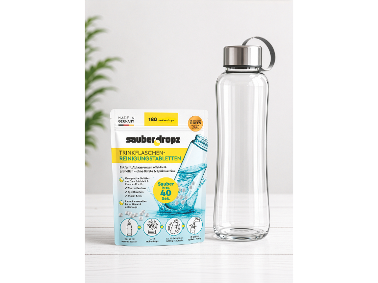 Beutel mit Reinigungstabletten für Trinkflaschen neben einer transparenten Glasflasche.