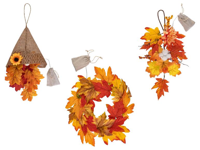 Herbstdekorationen mit Ahornblättern, Sonnenblume und Beeren, inklusive Kranz und Hängeornamenten.