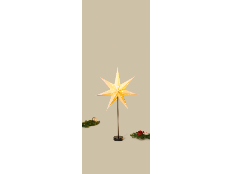 Leuchtender Weihnachtsstern auf einem schwarzen Ständer mit festlicher Dekoration.