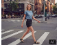 Eine Frau in blauem T-Shirt und schwarzen Denim-Shorts geht über einen Fußgängerüberweg in der Stadt.