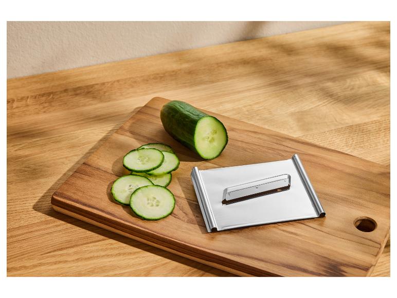 Geschnittene Gurke und Küchenmandoline auf einem Holzschneidebrett.