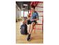 Mann in blauem T-Shirt, schwarzen Shorts und blauen Turnschuhen, sitzend mit Rucksack.