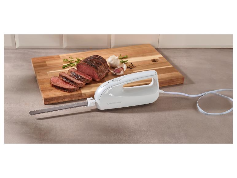 Ein weißes Elektromesser neben einem aufgeschnittenen Rinderbraten auf einem Holzschneidebrett.