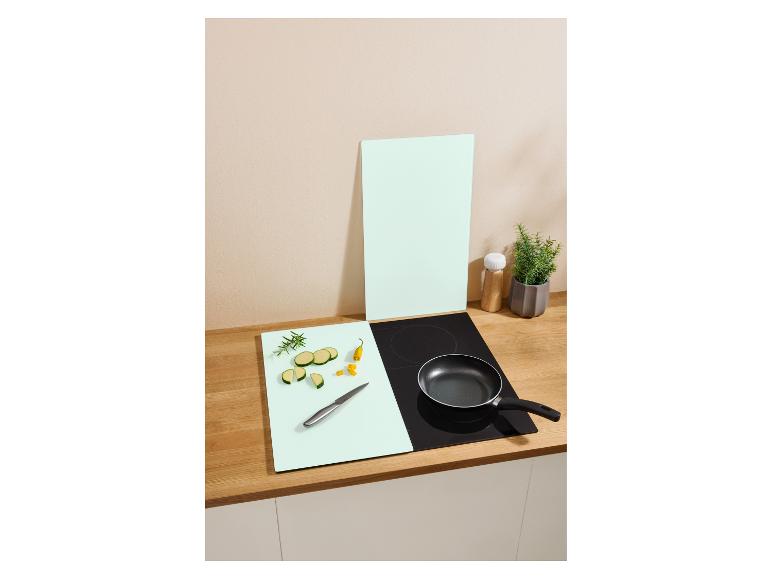 Küchenarbeitsplatte mit Schneidebrett, geschnittener Zucchini, Messer, Bratpfanne und Topfpflanze.