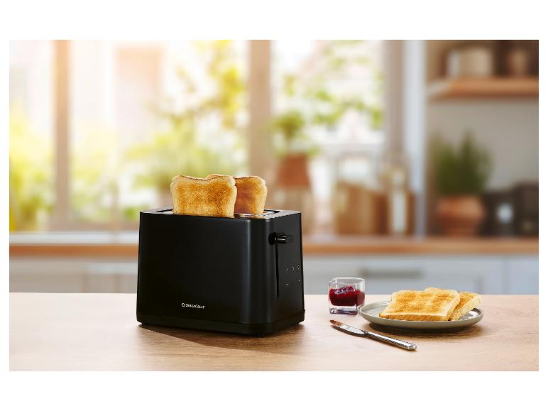 Schwarzer Toaster mit zwei Scheiben Toast, Marmelade und einem Messer auf einem Holztisch.