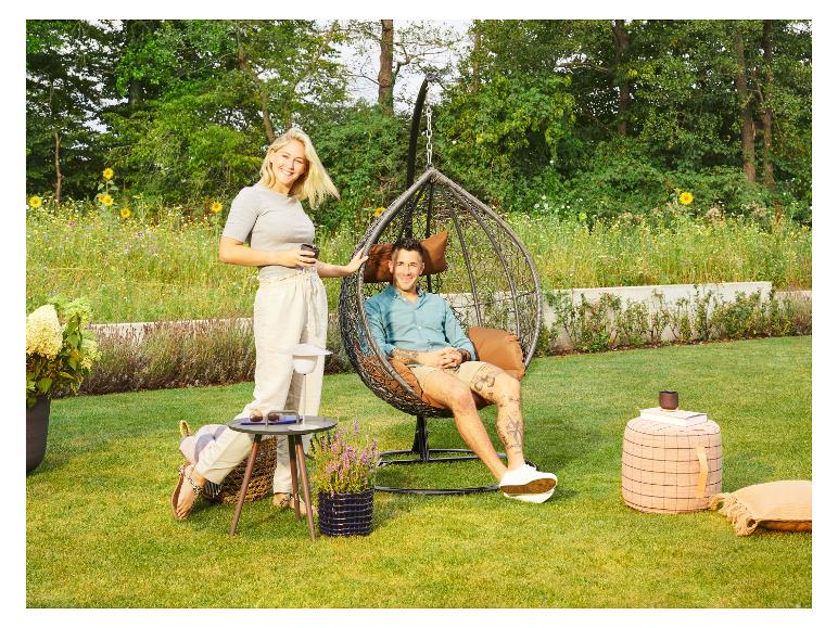 Paar entspannt im Garten mit Hängesessel, Beistelltisch und Außenbeleuchtung.