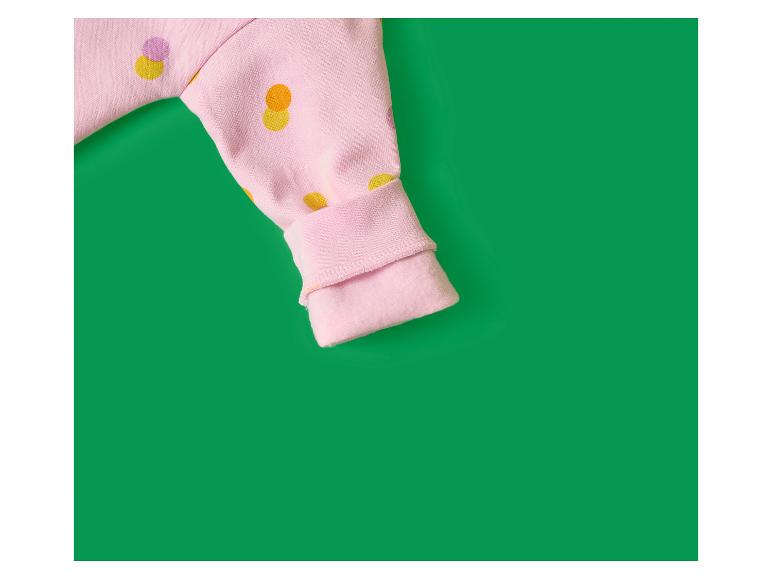 Rosa Ärmel mit bunten Punkten auf grünem Hintergrund.