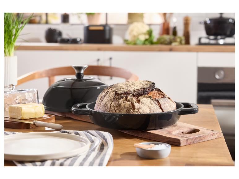 Brot in einer schwarzen Gusseisenform auf einem Holztisch in einer hellen Küche.