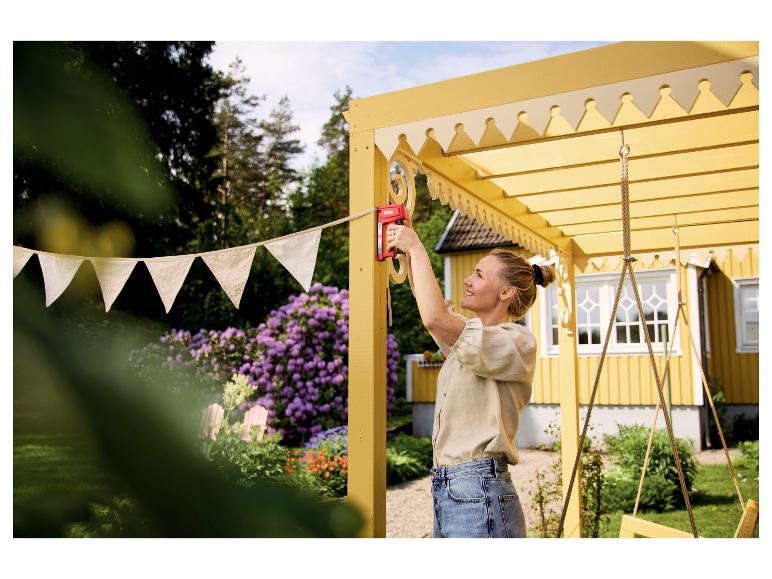 Frau befestigt Wimpel mit LIVARNO® Handtacker »R53 T&F« an einer gelben Pergola.