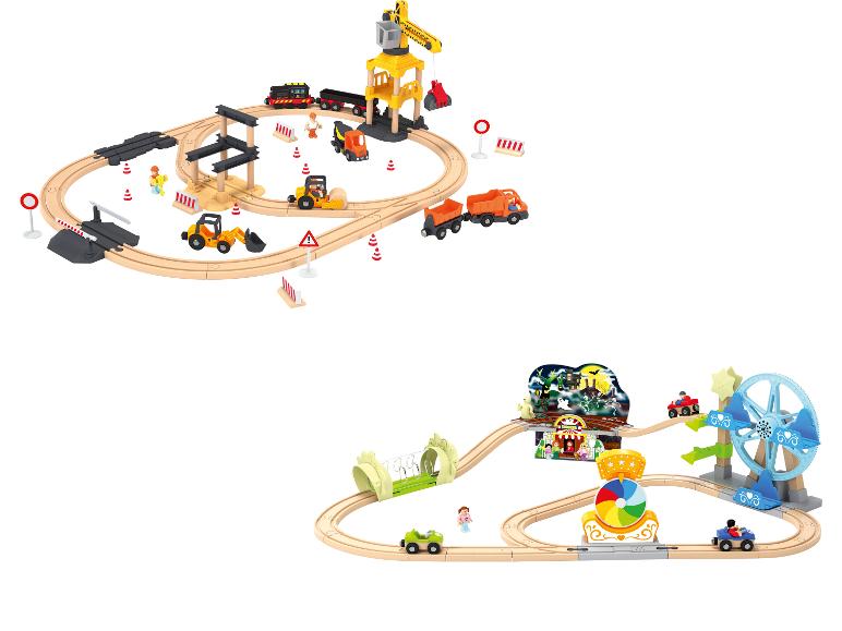 Zwei Holzeisenbahn-Sets: eine Baustelle mit Fahrzeugen und ein Jahrmarkt mit Fahrgeschäften.