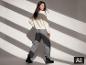 Frau im weißen ESMARA Mohair-Mix-Pullover und grauer Hose. [KI-generiertes Bild]