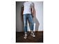 Mann in weißem T-Shirt mit Text und blauer Jeans mit umgekrempelten Säumen, schwarze Sneaker.