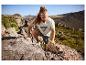 Mann in Sport-T-Shirt und Shorts klettert in den Bergen auf Felsen.