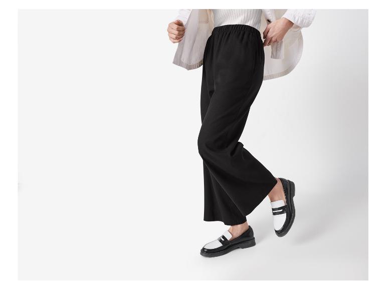 Weite schwarze Hose und zweifarbige Loafer.