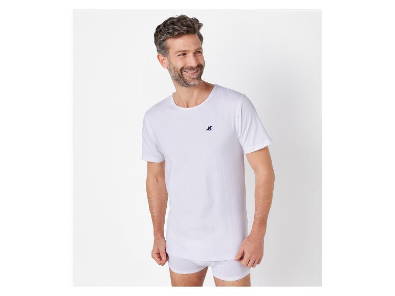 Ein Mann trägt ein weißes T-Shirt mit einem kleinen Logo.