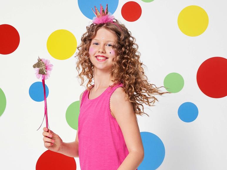 Ein Mädchen mit einem rosa Oberteil und einem Einhorn-Zauberstab vor einem Hintergrund mit bunten Punkten.