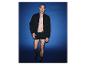 Mann in schwarzer Bomberjacke und Boxershorts vor blauem Hintergrund.