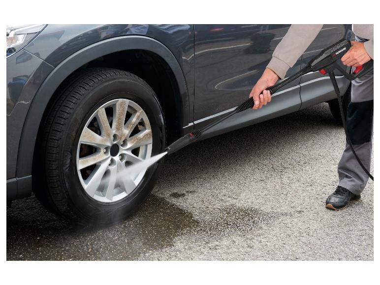 Mann wäscht ein schmutziges Autoreifen mit einem Hochdruckreiniger.