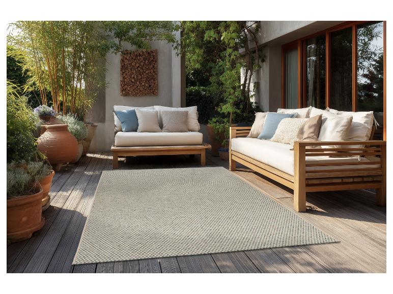 Terrasse mit Holz-Gartenmöbeln, hellen Kissen und gemustertem Teppich.