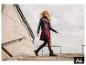 Frau in schwarzer ESMARA® Bikerjacke, weinrotem Kleid und Stiefeln geht eine Treppe hinunter. [KI-generiertes Bild]