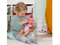 Mädchen füttert Puppe mit rosa Mütze und Kleidung.