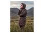 Frau in einer gesteppten Kapuzenjacke in einer bergigen und grasbewachsenen Landschaft.