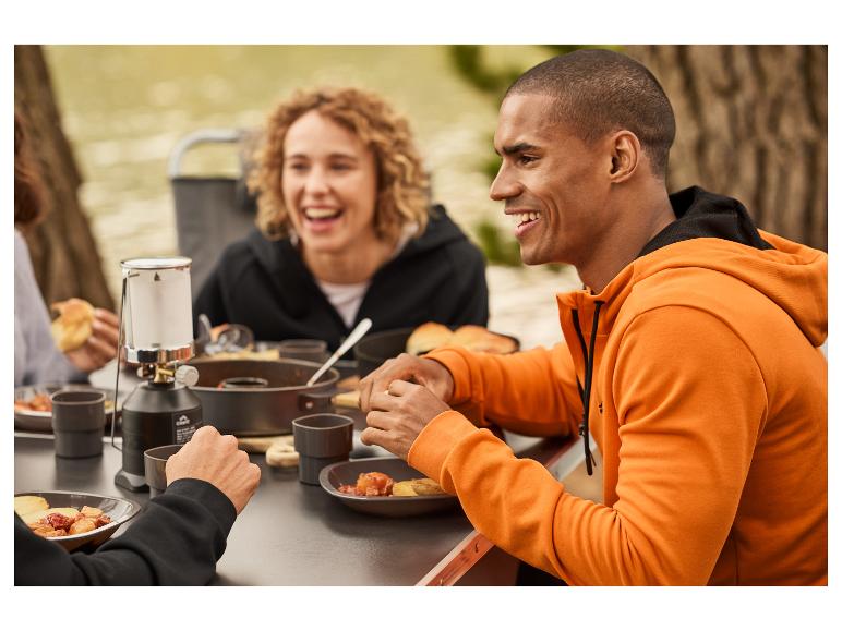 Outdoor-Essen mit Primus-Lampe und orangener Kleidung.