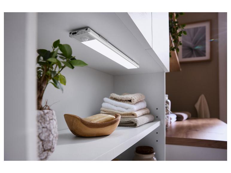 Eine LED-Schrankleuchte mit Bewegungssensor unter einem weißen Schrank, mit Handtüchern und Seife.