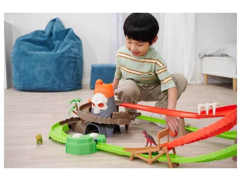 Ein Junge spielt mit einem Dinosaurier- und Vulkan-Spielset.