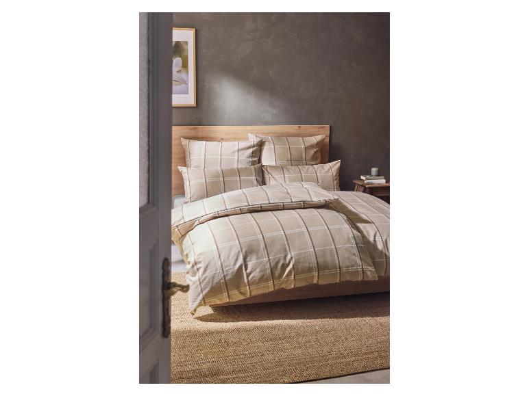 Schlafzimmer mit beiger karierter Bettwäsche und Holzmöbeln