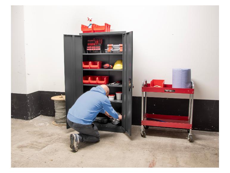 Mann kniet vor einem Metallwerkzeugschrank mit Aufbewahrungsboxen in einer Garage.