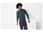 Mann mit Afrofrisur in dunkelgrünem Pullover und schwarzer Jeans.