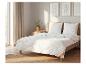 Schlafzimmer mit Bett, weißer gesteppter Bettwäsche, Kissen und Holzrahmen.