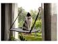 Schwarz-weiße Katze sitzt auf einem Fensterbrett, mit grünen Bäumen im Hintergrund.