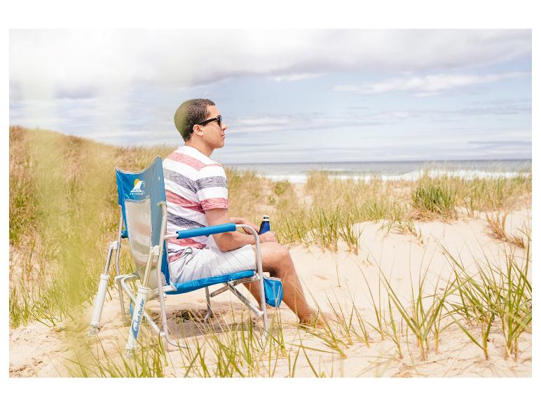 Ein Mann sitzt auf einem GCI-Strandstuhl am Strand.