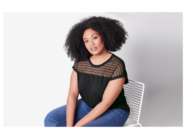 Model in einem schwarzen Spitzentop und Jeans.