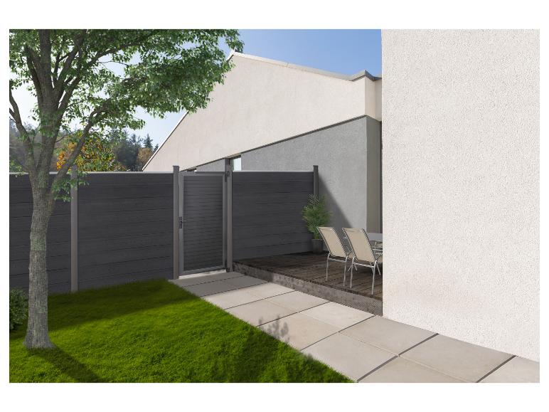 Moderner Garten mit dunkelgrauem Zaun und Tor, Holzterrasse, Gartenmöbeln und einem Baum.