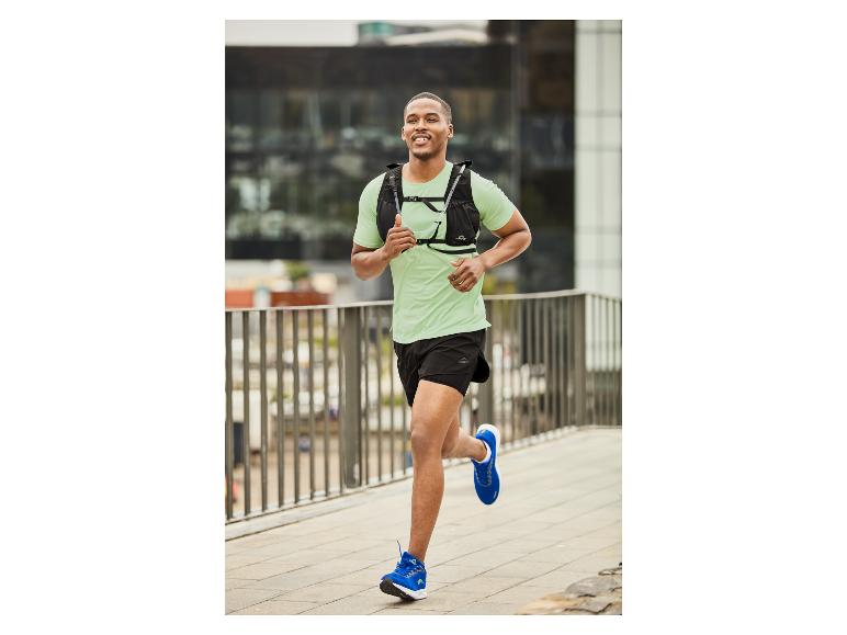 Mann läuft in der Stadt mit T-Shirt, Shorts und Crivit Rucksack.