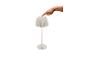 Weiße Tischlampe mit plissiertem Schirm und einer Hand, die den Einschaltknopf drückt.