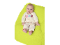 Glückliches Baby in gelbem Blumenoutfit, liegend auf einer grünen Decke.