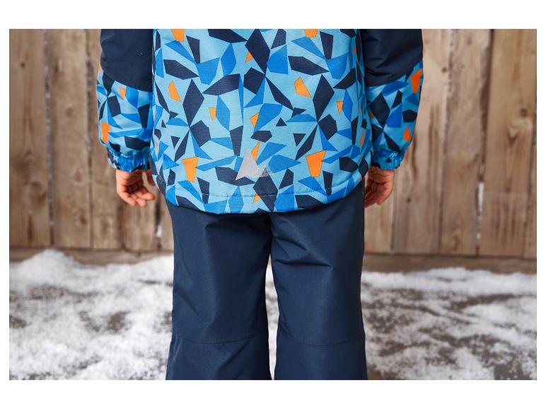 Ein Kind trägt eine blaue Skijacke mit geometrischem Muster und eine dazu passende blaue Hose.