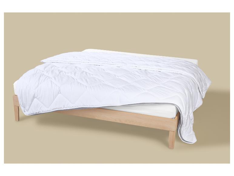 Weiße Bettdecke auf einem hellen Holzrahmenbett