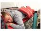 Ein Mann schläft in einem roten Schlafsack in einem Zelt.