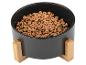 Schwarzer Haustiernapf mit Holzständer, gefüllt mit Trockenfutter.