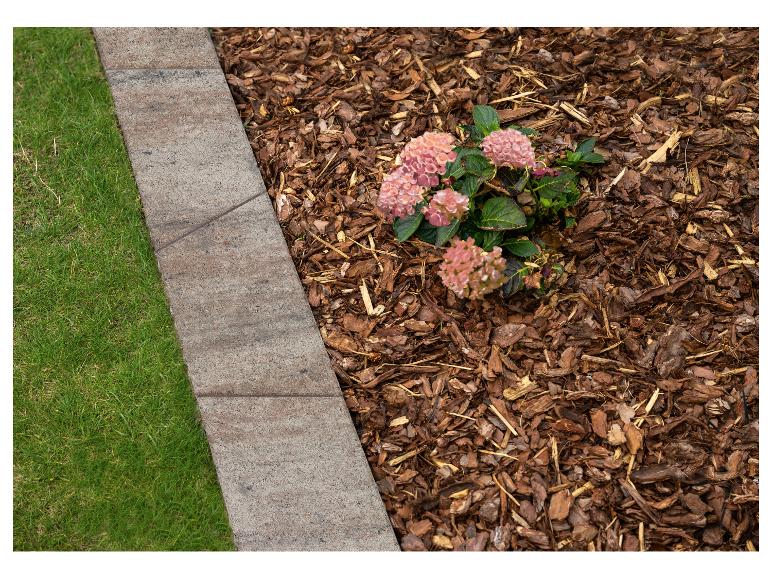 Steinerne Gartenbegrenzung mit Rindenmulch und rosa Hortensien.