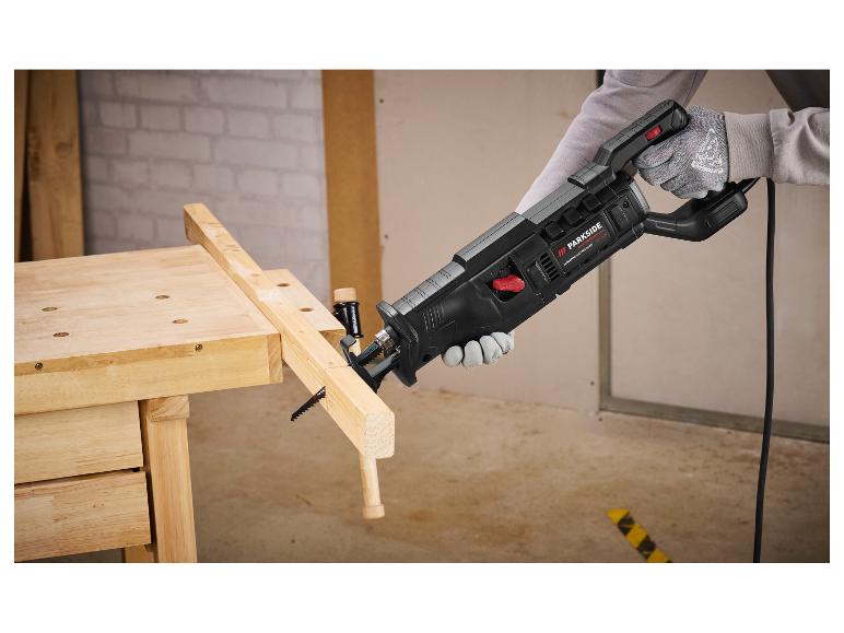 Parkside Performance Säge schneidet Holz auf Werkbank, mit Handschuhen.