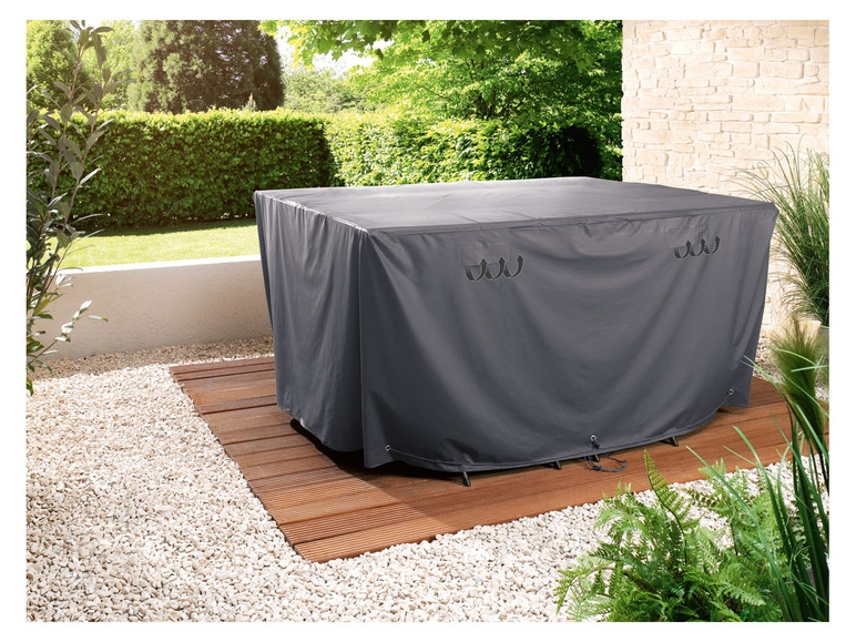 Eine graue Schutzhülle für einen Gartentisch und Stühle.